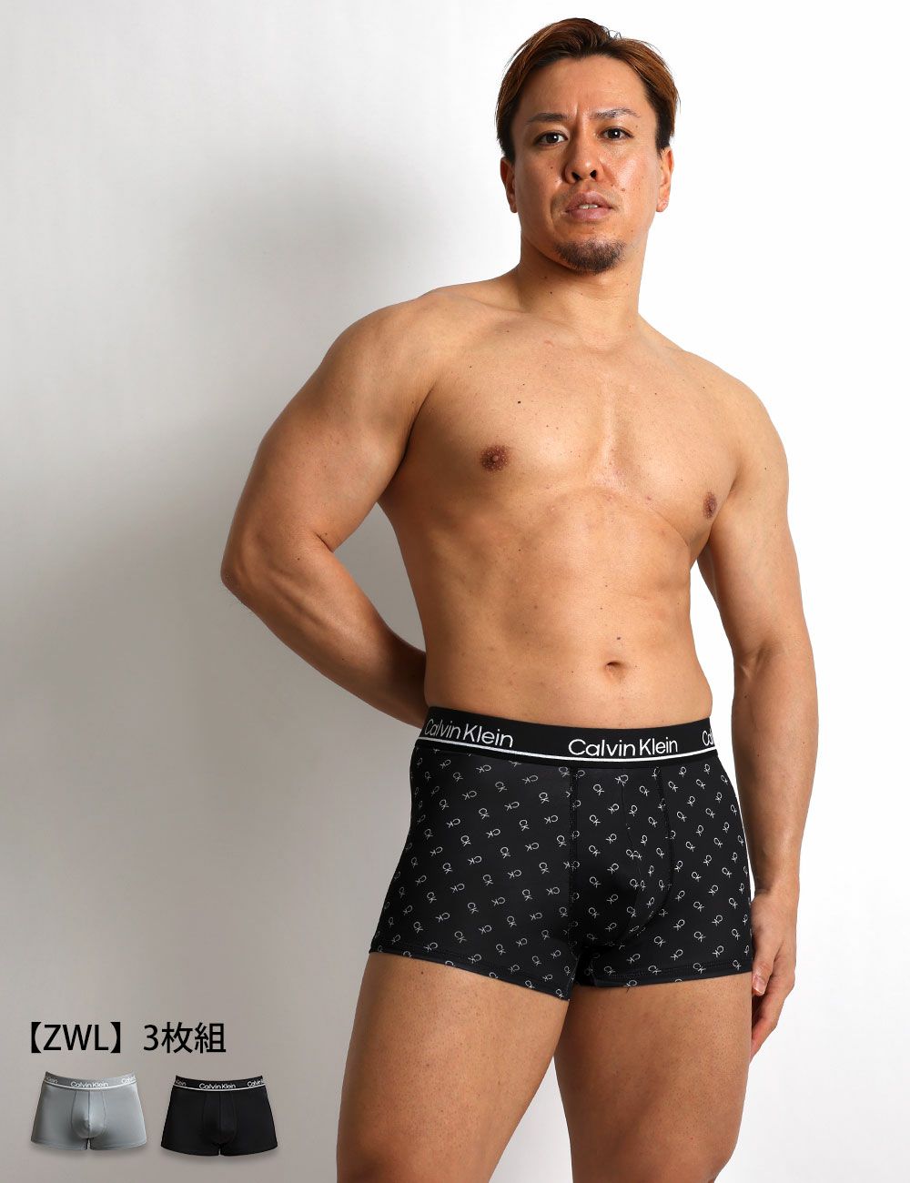 男性モデルがCalvin Kleinのブラック柄入りローライズボクサーパンツを着用。 スタイリッシュな総柄デザインと滑らかなウエストバンドが特徴の3枚セット。