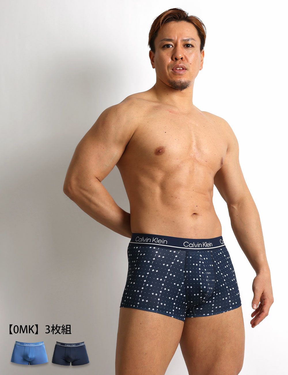 男性モデルがCalvin Kleinのネイビー柄ローライズボクサーパンツを着用。 マイクロファイバー素材の通気性と伸縮性に優れ、デイリーユースに最適な3枚セット。 商品名：CK Microfiber Plus メンズ下着。